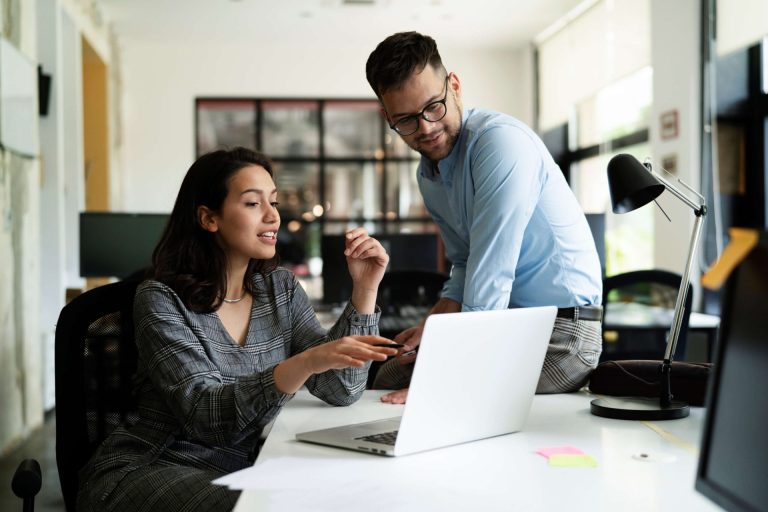 two coworkers chat about work project at desk scaled 1
